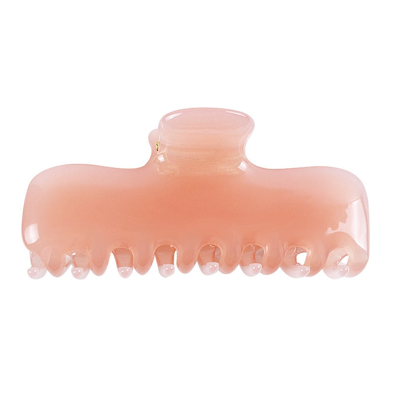 A translucent peach-pink hair claw clip on a solid white background.
