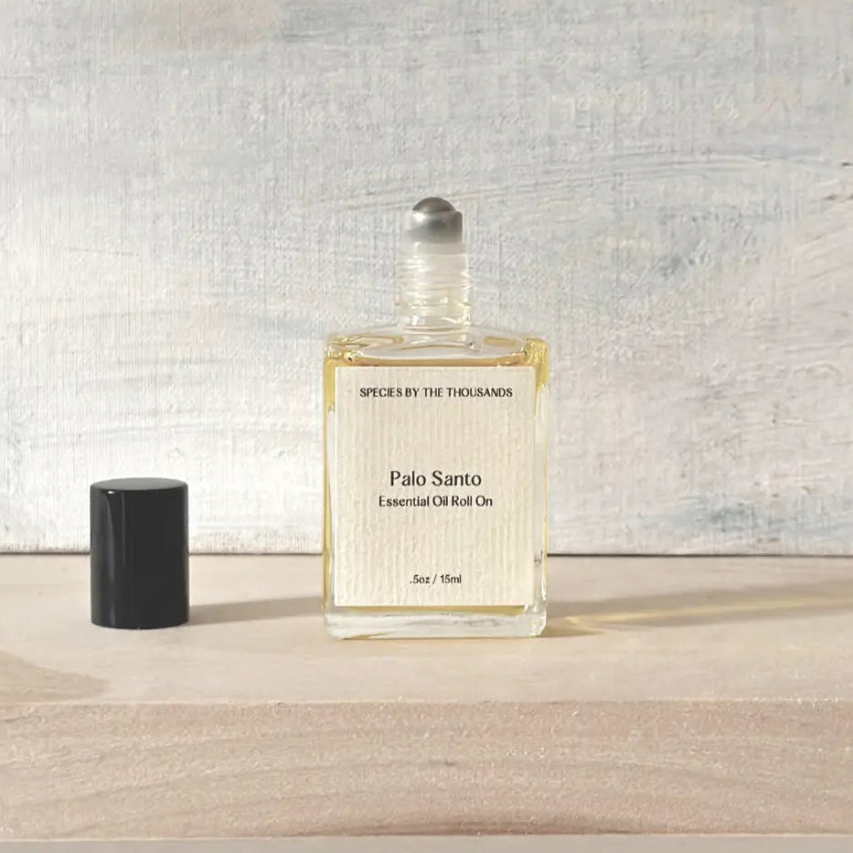 Bottle of Palo Santo essential oil roll-on on a wooden surface with a textured gray wall background