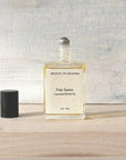 Bottle of Palo Santo essential oil roll-on on a wooden surface with a textured gray wall background