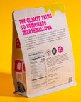 The back of the "S’more Speckled Marshmallows" package is displayed, continuing the bold design on a yellow backdrop. The text describes the product as "the closest thing to homemade marshmallows," detailing how they are crafted with chocolate chips and graham cracker dusting. Nutritional facts, ingredients, and certifications are also printed at the bottom of the package.