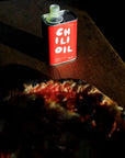 red chili oil bottle next to pizza