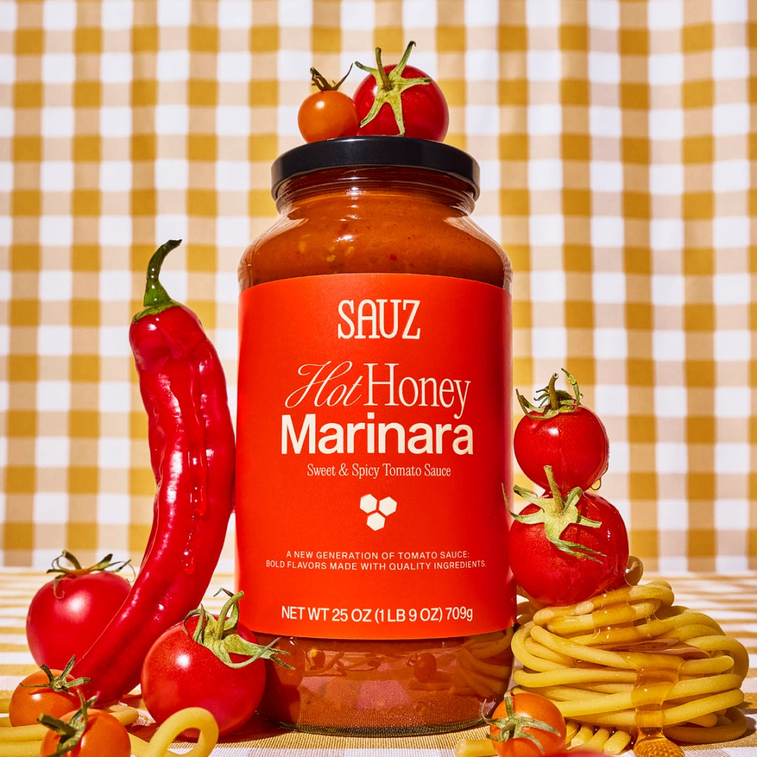 SAUZ Hot Honey Marinara sauce jar with tomatoes, a red pepper, and pasta on a checkered background