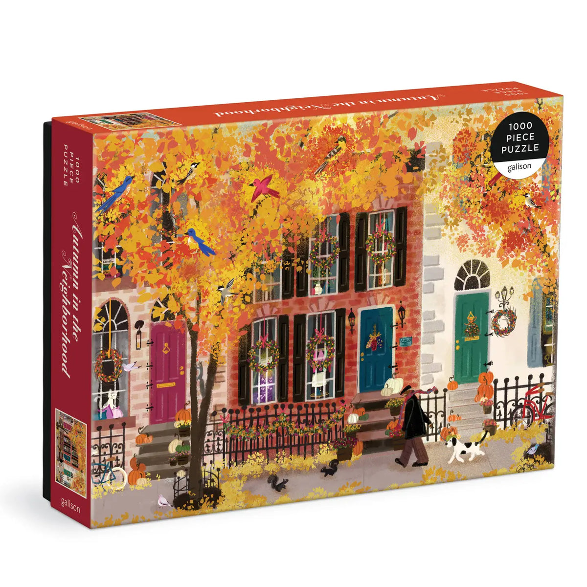 A boxed jigsaw puzzle on a clean white background. The box art shows a colorful autumn street scene with a row of houses, bright orange and yellow leaves, birds, flowers, and a person walking a dog.