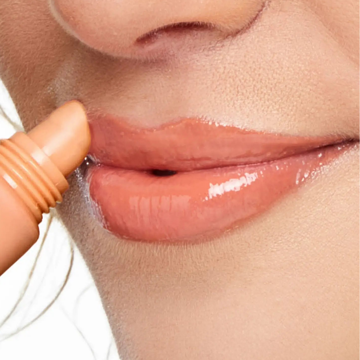 Close-up of a person applying lip gloss to their lips.