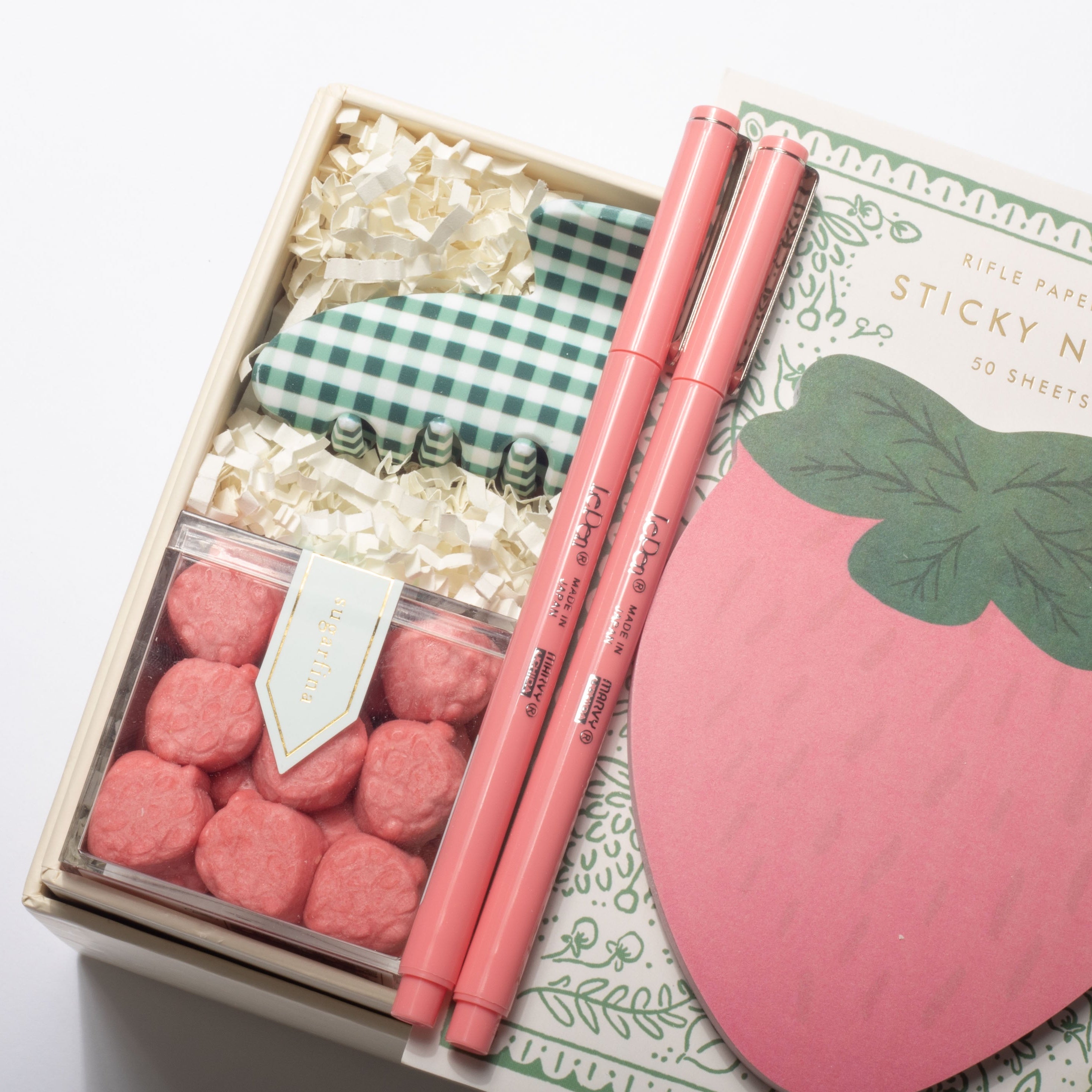 Stationery set with pink strawberry-shaped sticky notes, pens, and decorative items in a box.