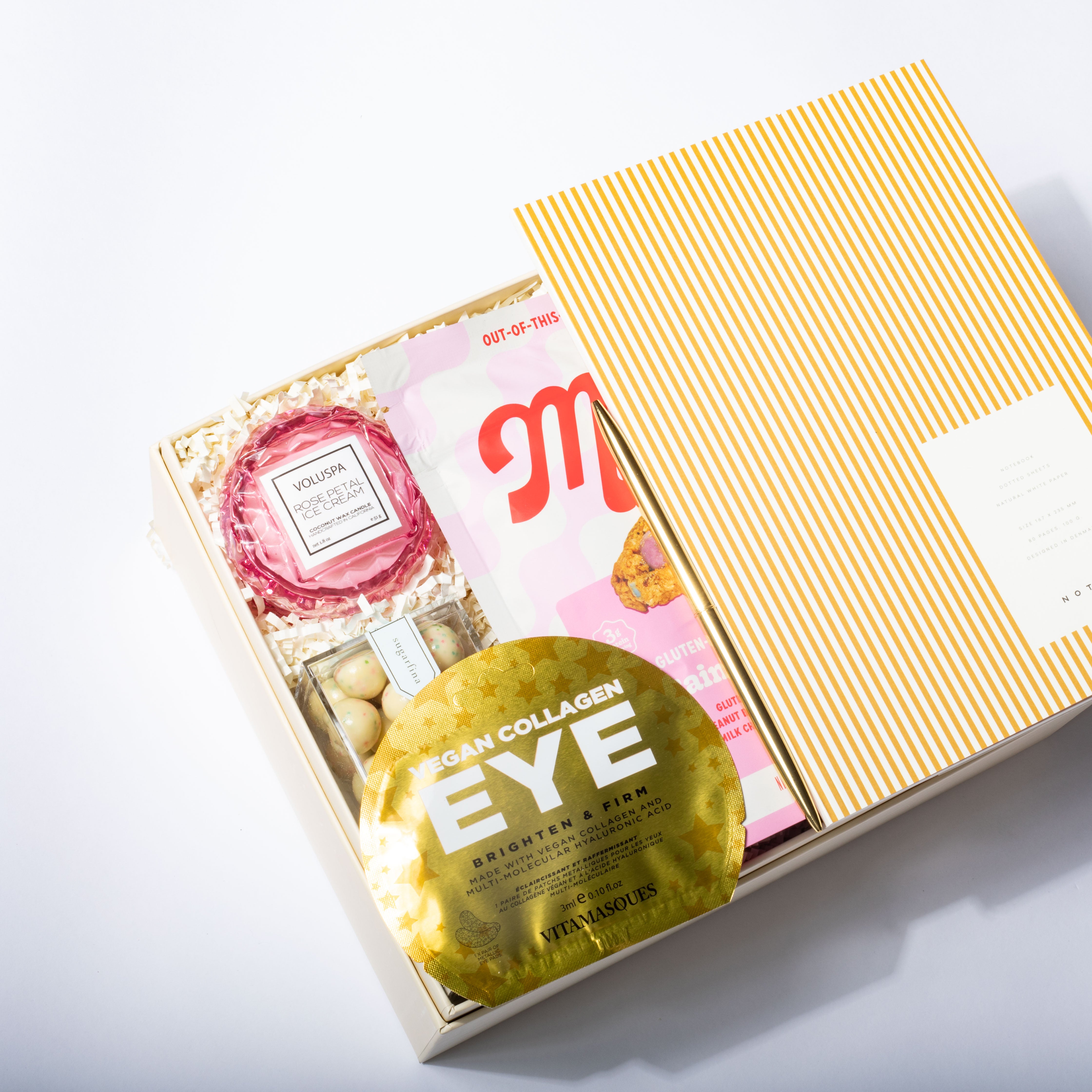 Skincare product packaging with a gold eye mask and pink container on a white background