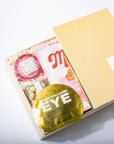 Skincare product packaging with a gold eye mask and pink container on a white background