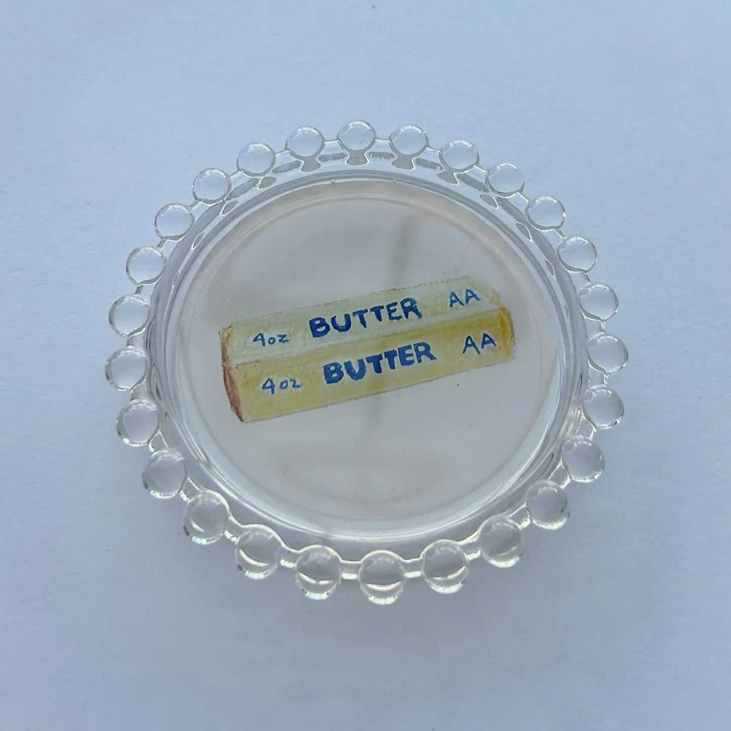 Clear container lid with 'BUTTER AA' label on a white background