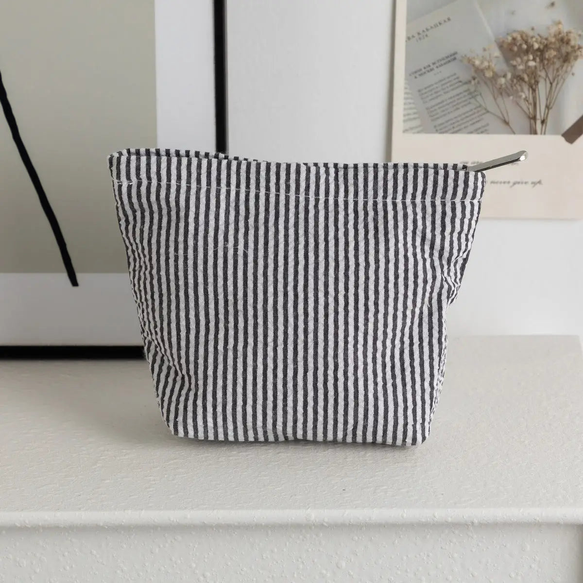 Black and white striped fabric basket on a light surface with a neutral background