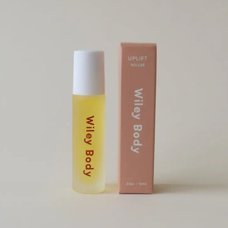 Yellow rollerball bottle with white cap and pink box on a light gray background
