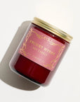 Red candle with gold top and gold writing that states "ancient myrth soy candle" 
