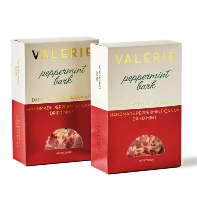 Two packages of "Valerie Peppermint Bark" are shown. The packaging is a combination of cream and red colors. The top part reads "VALERIE" in gold text and "peppermint bark" in elegant green script. Below it states "Dark & White Chocolate" and "Handmade Peppermint Candy, Dried Mint." A small transparent semicircular window reveals the peppermint bark inside. The net weight is labeled as 200g.






