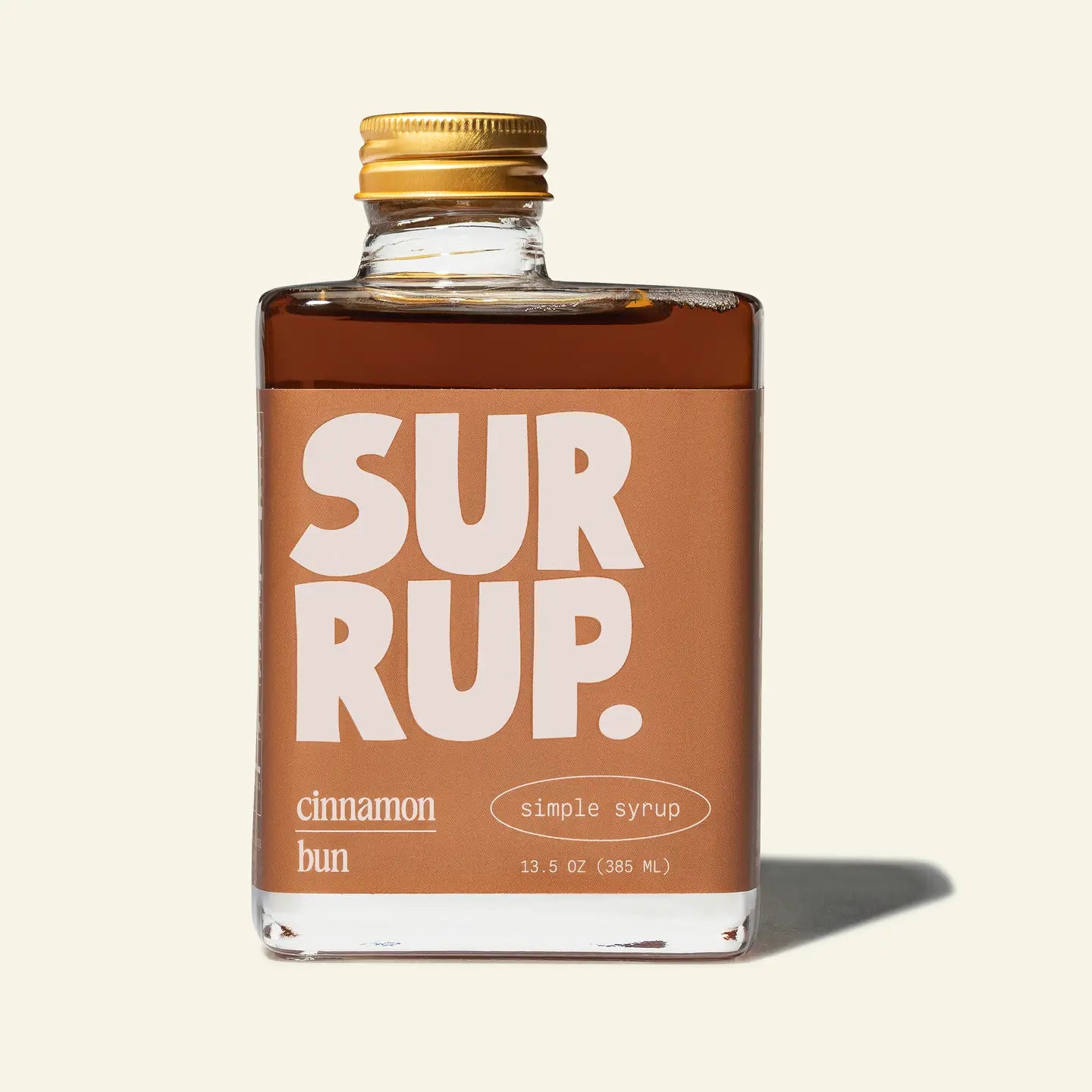 Bottle of 'Sur Rup' cinnamon bun simple syrup with a gold cap on a beige background