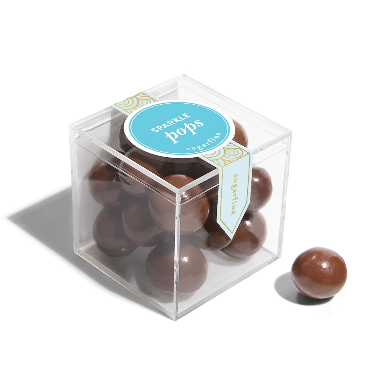 Clear cube box with chocolate spheres and a blue label on a white background