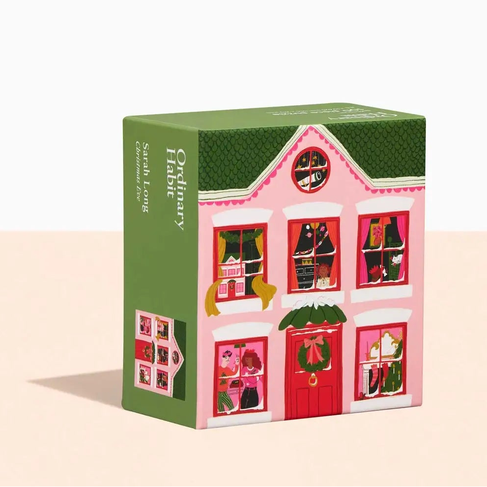 Small house-shaped box with a green roof and pink body on a beige background