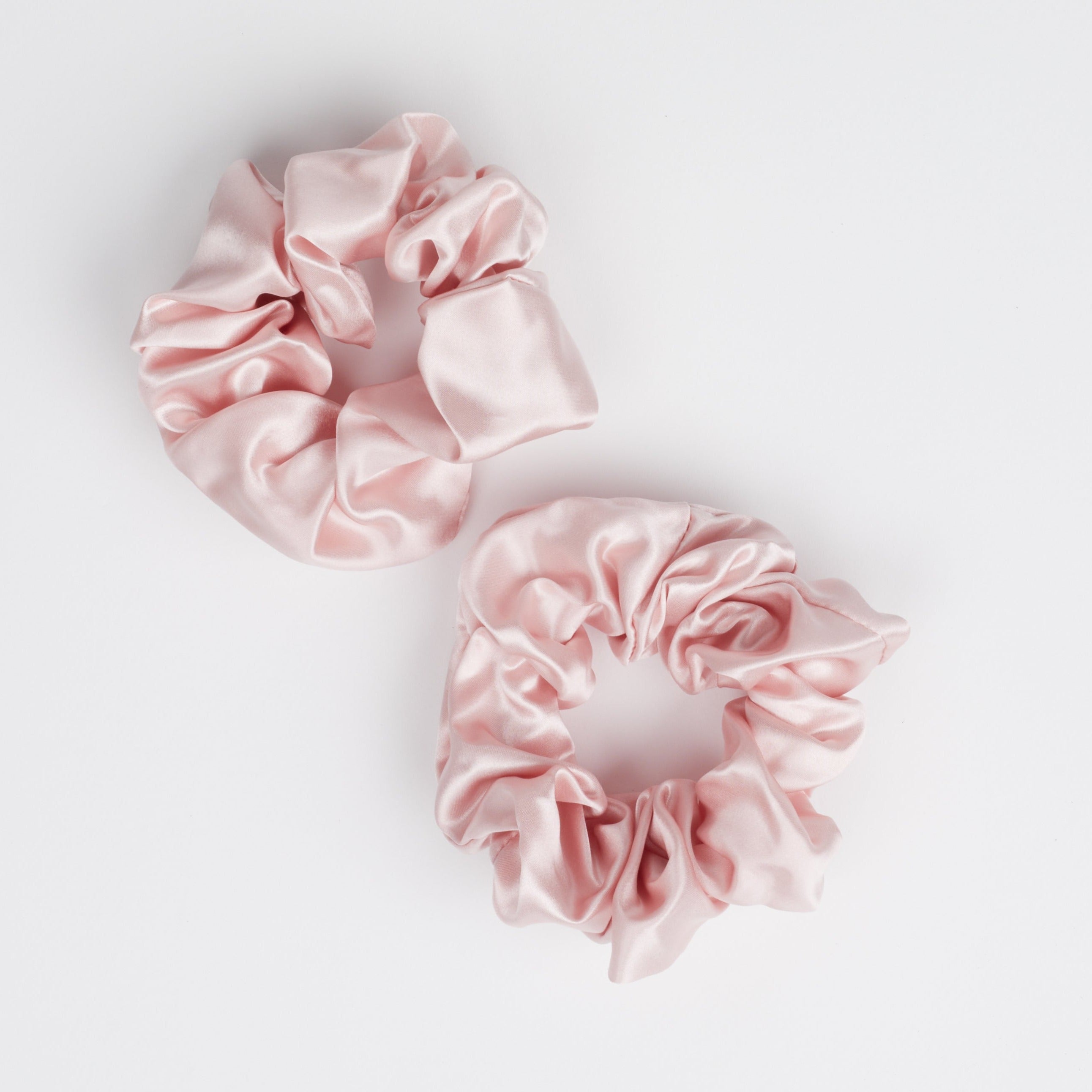 Two pink thick silk scrunchies on white background.