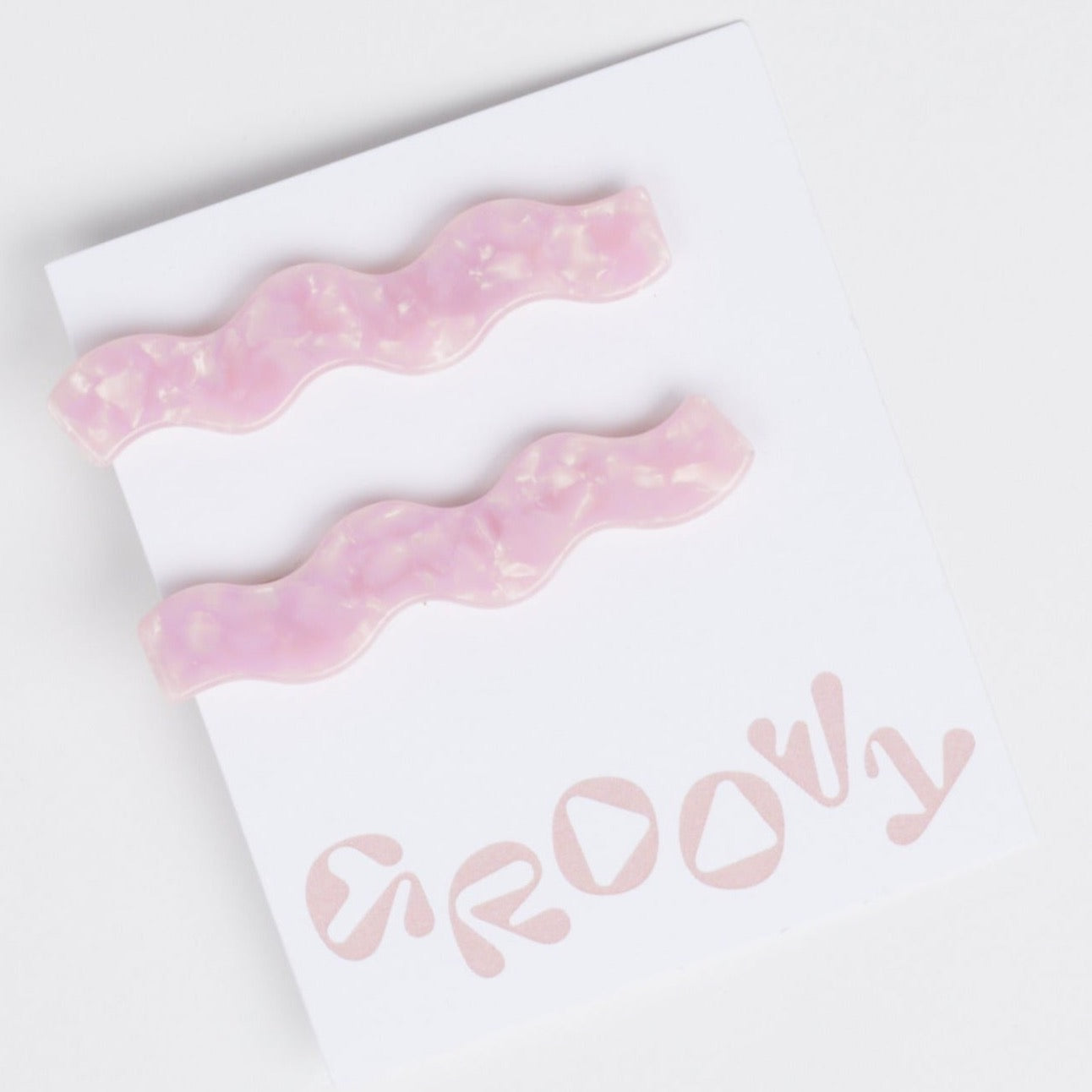 A set of two wavy pink acrylic hair barrettes against a white background.