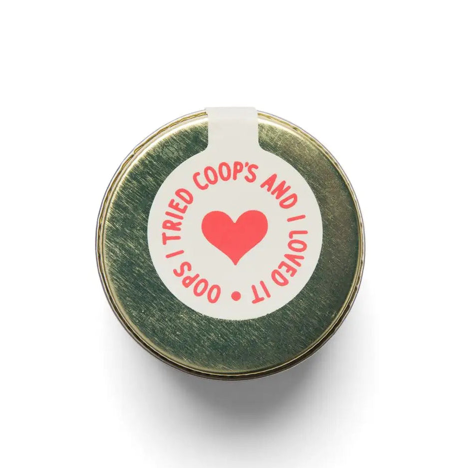 Round green metal object with a white label featuring a red heart and text on a white background