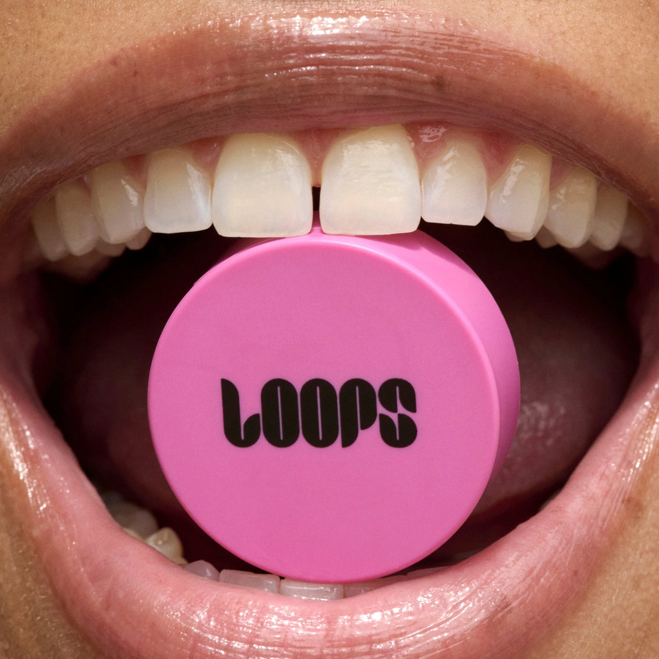 Pink lip balm with 'LOOPS' branding in a mouth