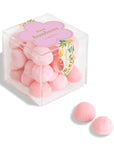 Clear box of pink bonbons with a decorative label on a white background