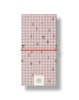A vertical notebook or journal with a pastel pink and blue gingham pattern, decorated with small floral motifs. It is secured with a bright orange elastic band and features a white paper label at the bottom with the brand name 'PAPIER'.