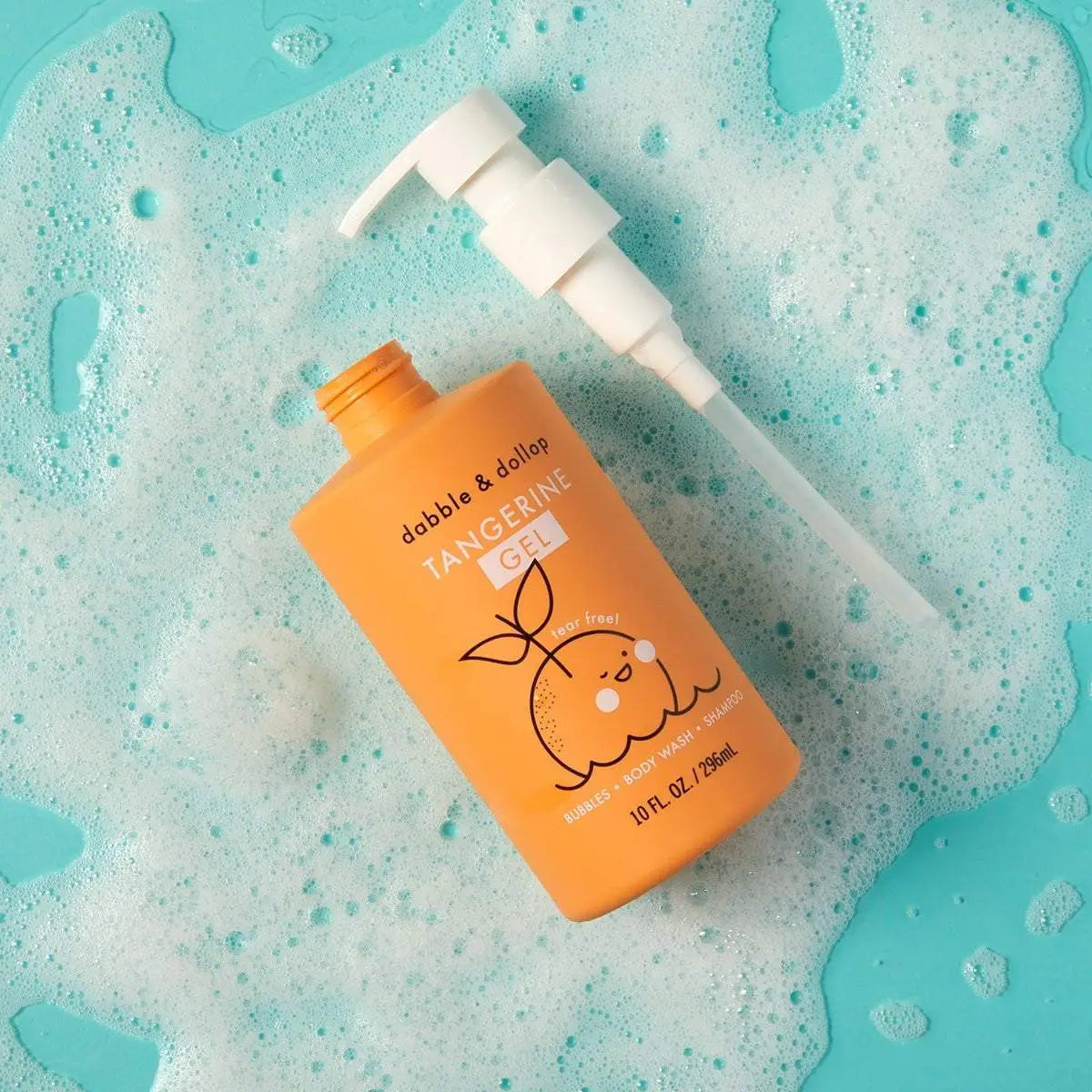 An orange bottle of dabble &amp; dolly Tangerine Gel bath bomb with a white pump dispenser, placed on a light blue background covered in white foam bubbles.