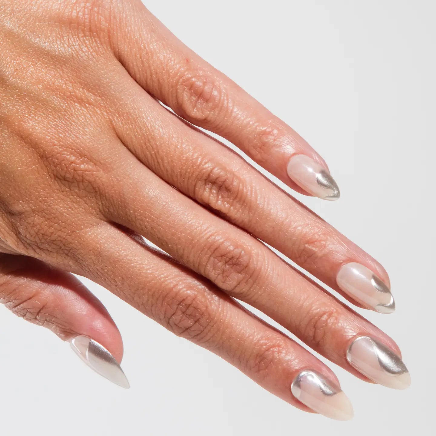Close-up of a hand with silver and clear nail polish on a light gray background
