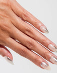 Close-up of a hand with silver and clear nail polish on a light gray background