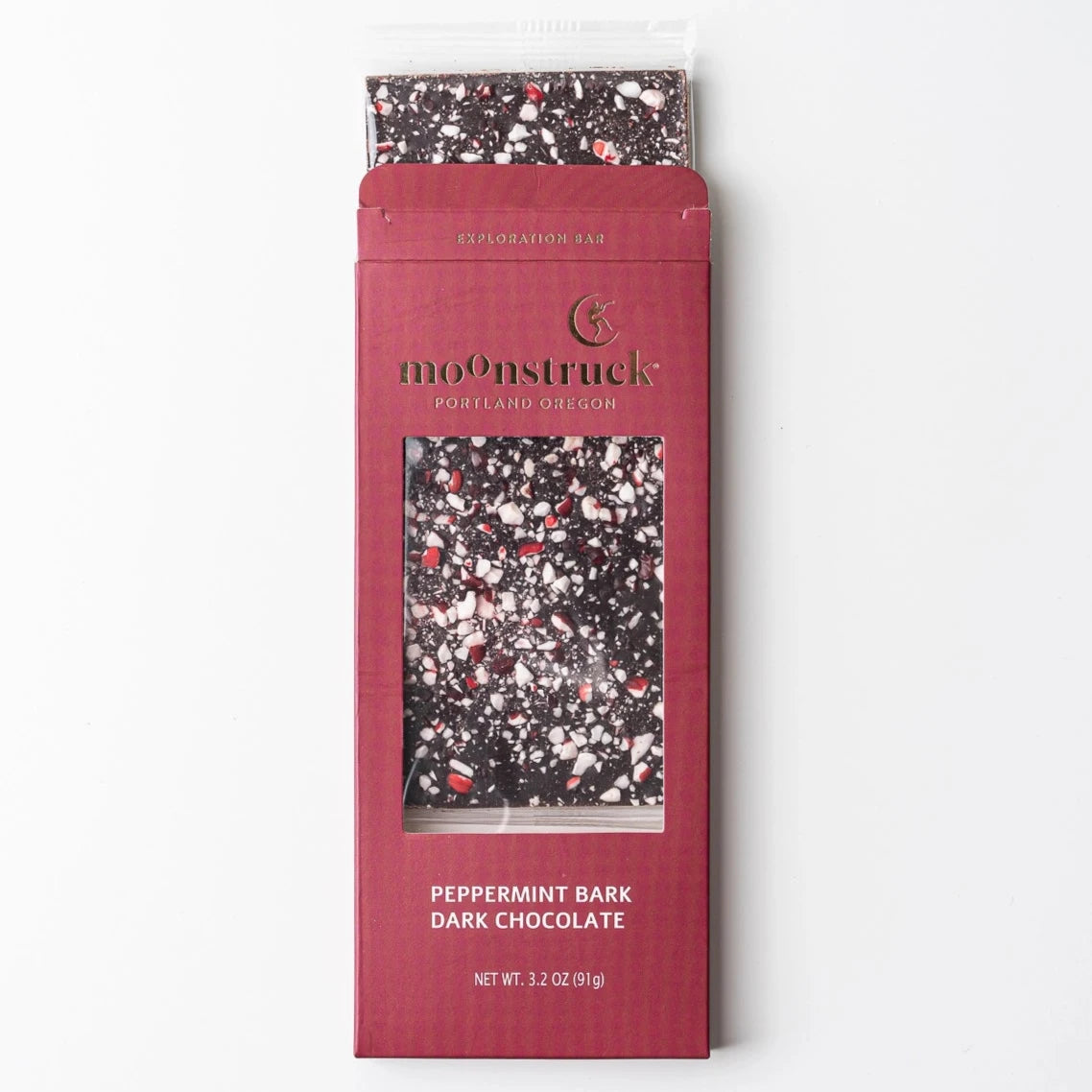 Peppermint Bark Dark Chocolate" bar from Moonstruck, with a maroon packaging design. The bar itself has a speckled look with pieces of white and red peppermint on dark chocolate