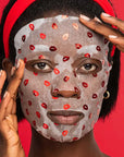 Person wearing a face mask with red lip prints against a red background