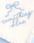 White fabric with blue embroidered text and bow on a light blue background
