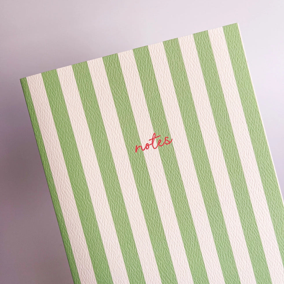 Green and white striped notebook on a white background