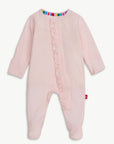 A baby's long-sleeve footed sleeper in light pink, featuring a ruffled trim down the front and a colorful striped inner collar, shown against a plain light background.