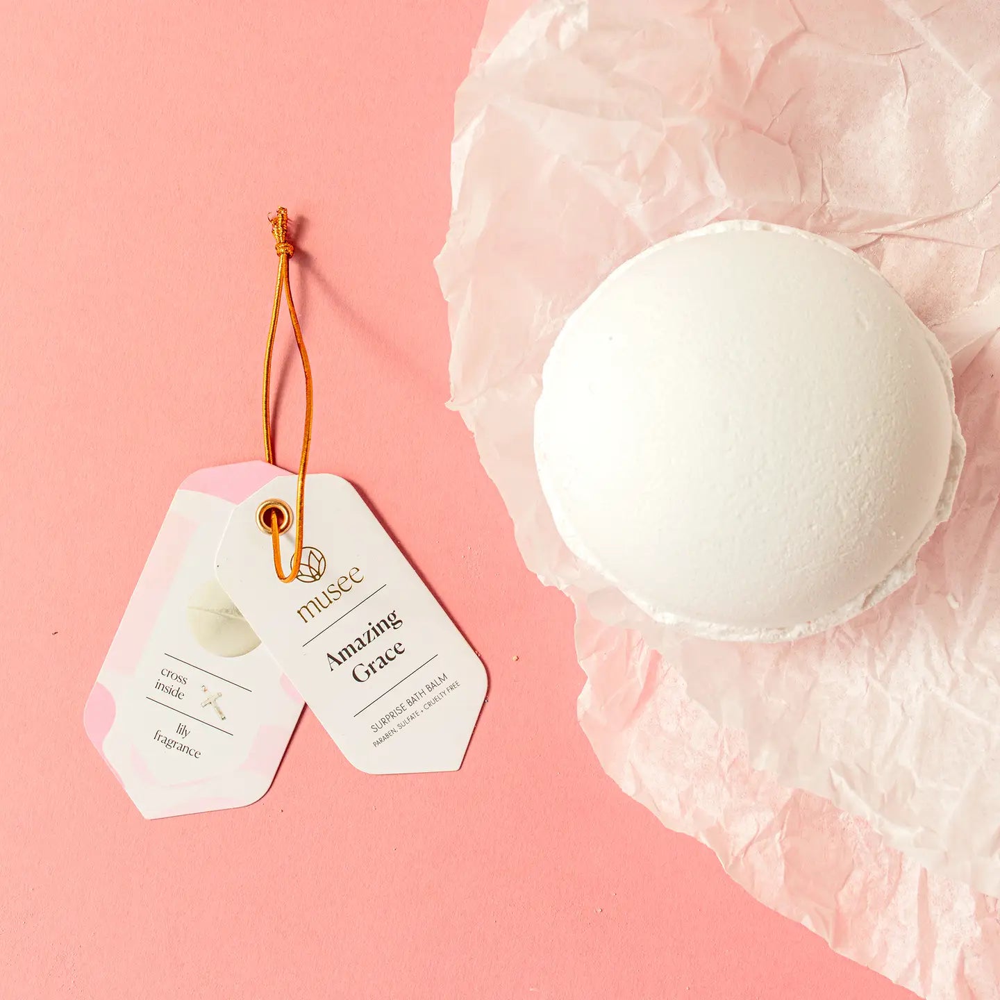White bath bomb with a tag on a pink background