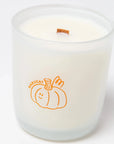 clear glass candle with an orange pumpkin that says "harvest" on it