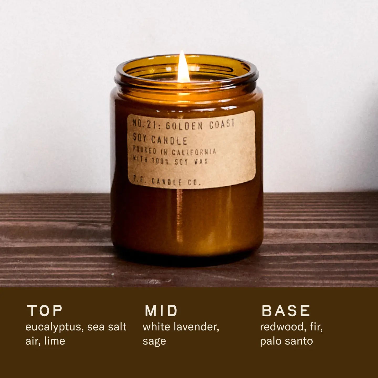 Brown candle with a label on a wooden surface, featuring notes of eucalyptus, sea salt, air, lime, white lavender, sage, redwood, fir, and palo santo.