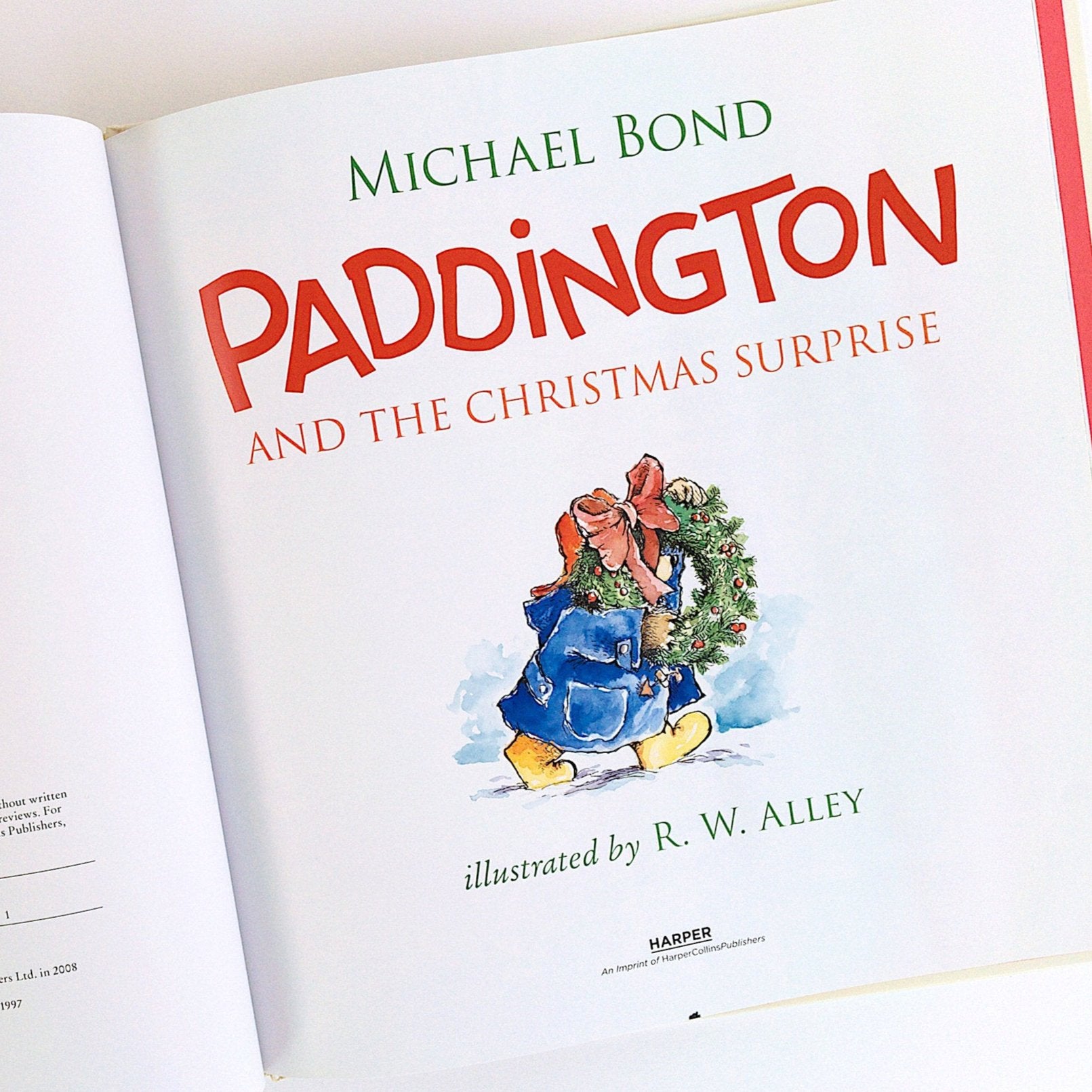 inside cover of paddington and the christmas surprise book with illustration of paddington bear carrying a wreath