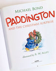 inside cover of paddington and the christmas surprise book with illustration of paddington bear carrying a wreath