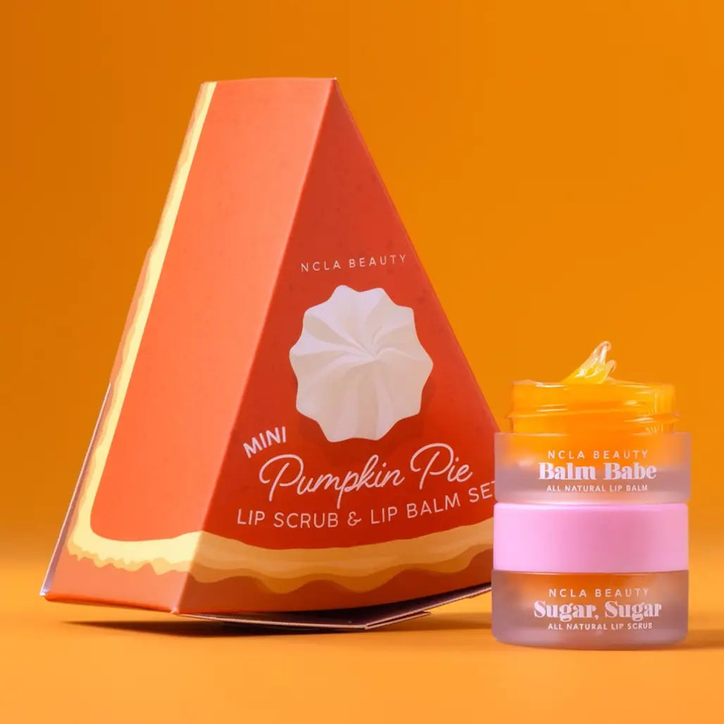 NCLA Beauty Mini Pumpkin Pie Lip Scrub &amp; Lip Balm Set, featuring a triangular orange packaging box and a small jar of lip balm with a pink lid, set against a solid orange background.