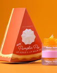 NCLA Beauty Mini Pumpkin Pie Lip Scrub & Lip Balm Set, featuring a triangular orange packaging box and a small jar of lip balm with a pink lid, set against a solid orange background.