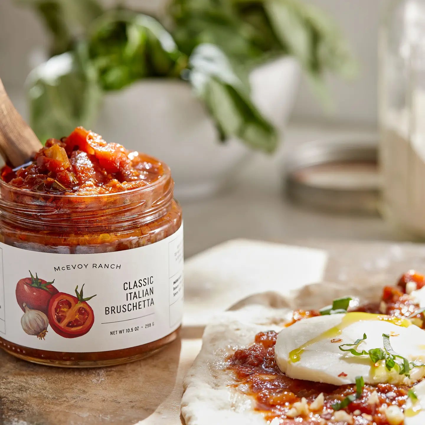 Jar of McEvoy Ranch Classic Italian Bruschetta spread on a wooden surface with a blurred background.