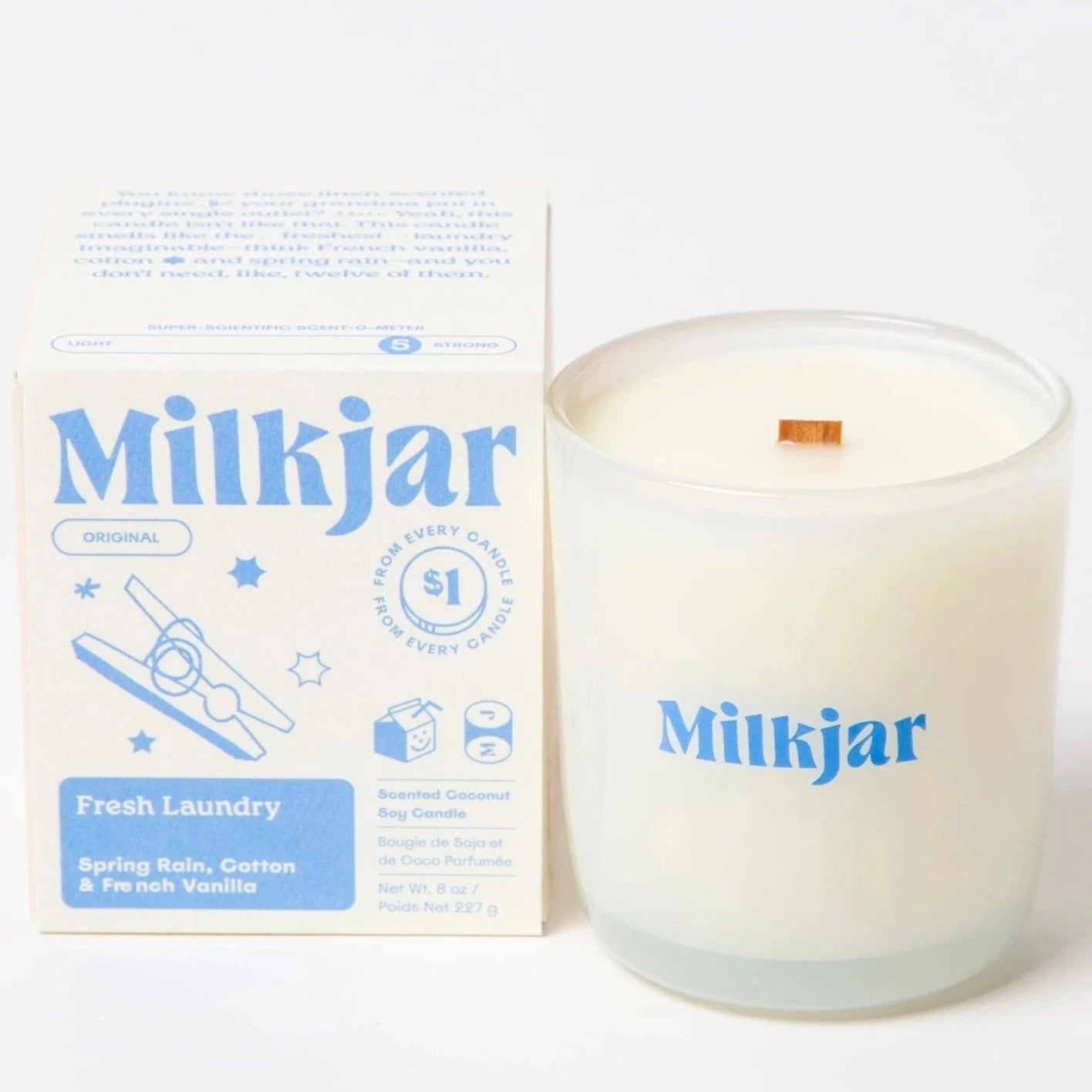clear glass candle with "MILKJAR" printed on it in blue next to packaging box 