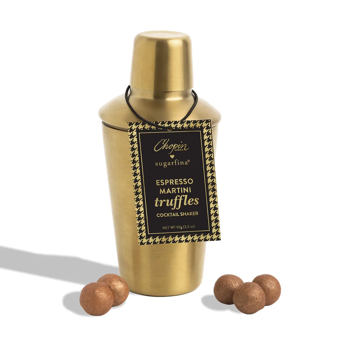 A gold cocktail shaker tin with a black and gold hanging label reading 'Chicory Sugarfina Espresso Martini Truffles Cocktail Shaker,' shown on a white background with several brown truffles placed in front.