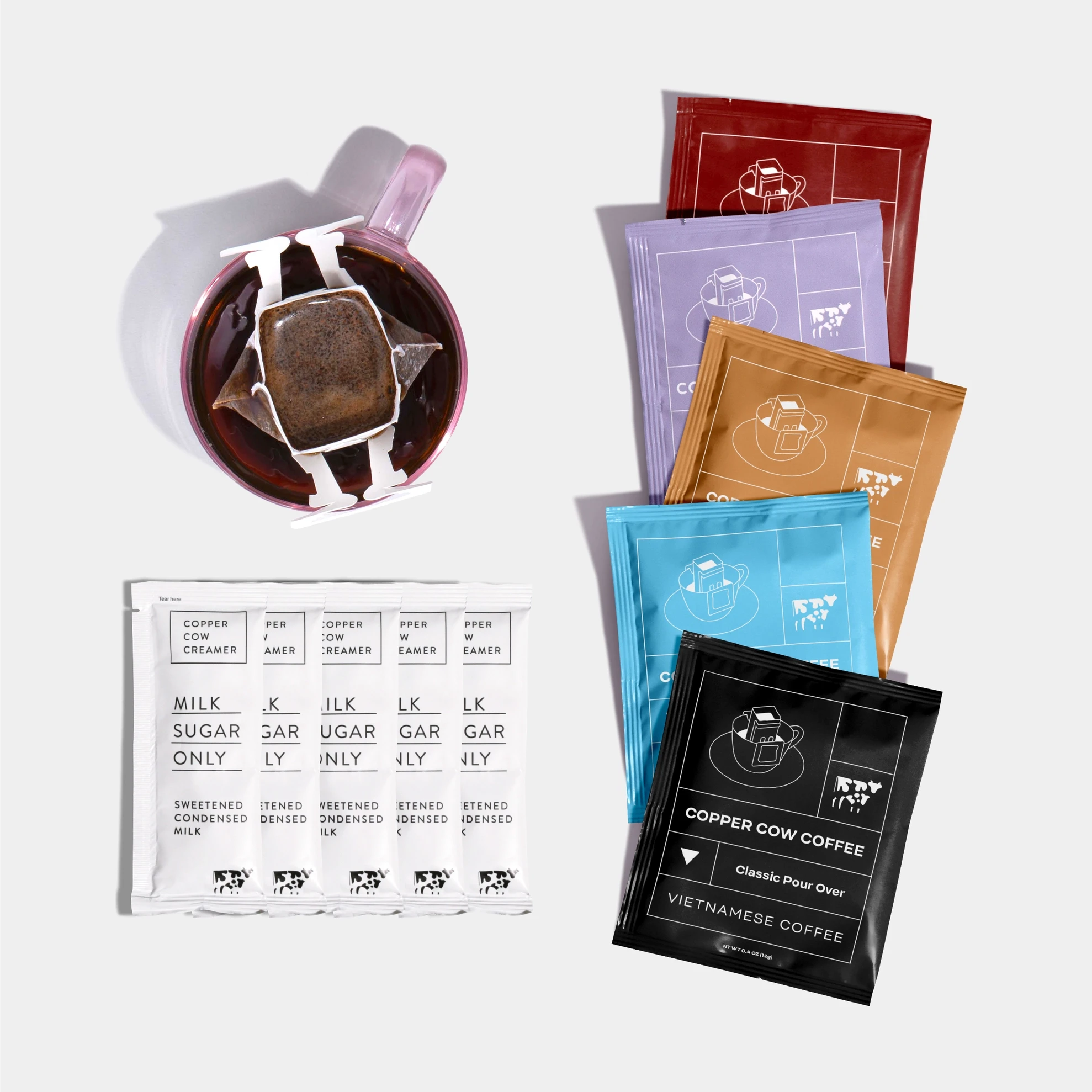 coffee mug with white creamer packets and colorful sachets of the different coffees 