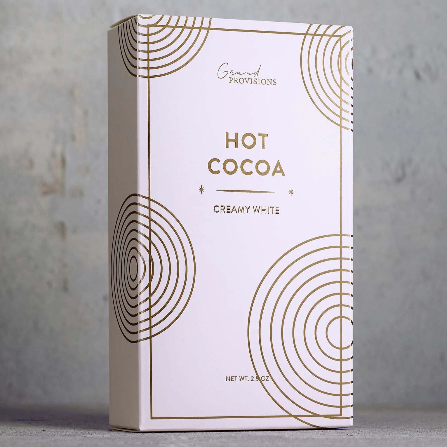 Hot cocoa packaging with gold circular designs on a gray background