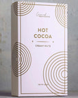 This image shows a sleek and minimalistic packaging design for a "Hot Cocoa" product, specifically labeled "Creamy White" by "Grand Provisions." The design features a light background with geometric circular patterns in gold, giving it a modern and premium look. The packaging highlights the product’s weight (2.5 oz) at the bottom.

