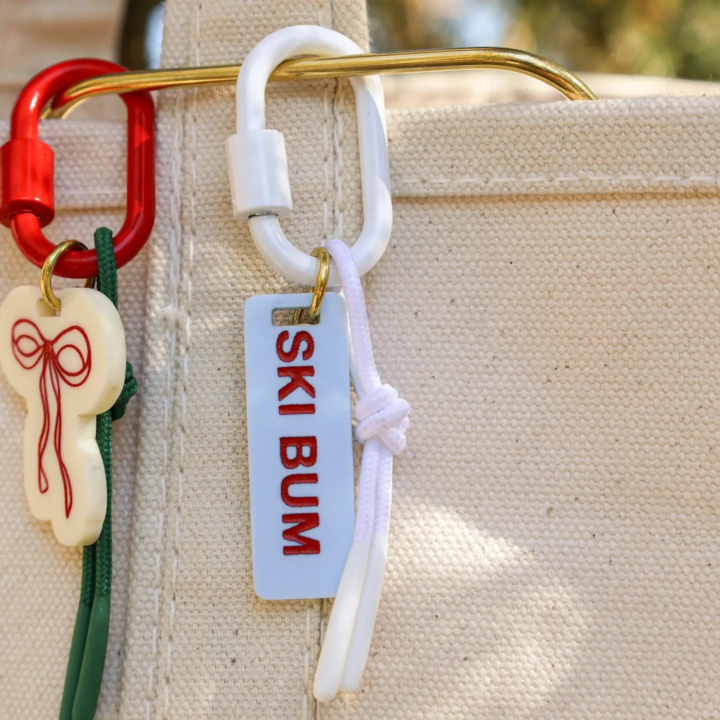 Keychain with 'Ski Bum' tag attached to a beige bag