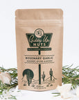 Kraft paper packaging of Giddy Up Nuts Rosemary Garlic almonds with decorative elements on a light background