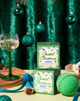 Coastal Christmas bath bombs and packaging on a festive table with a glass of wine and decorative items.