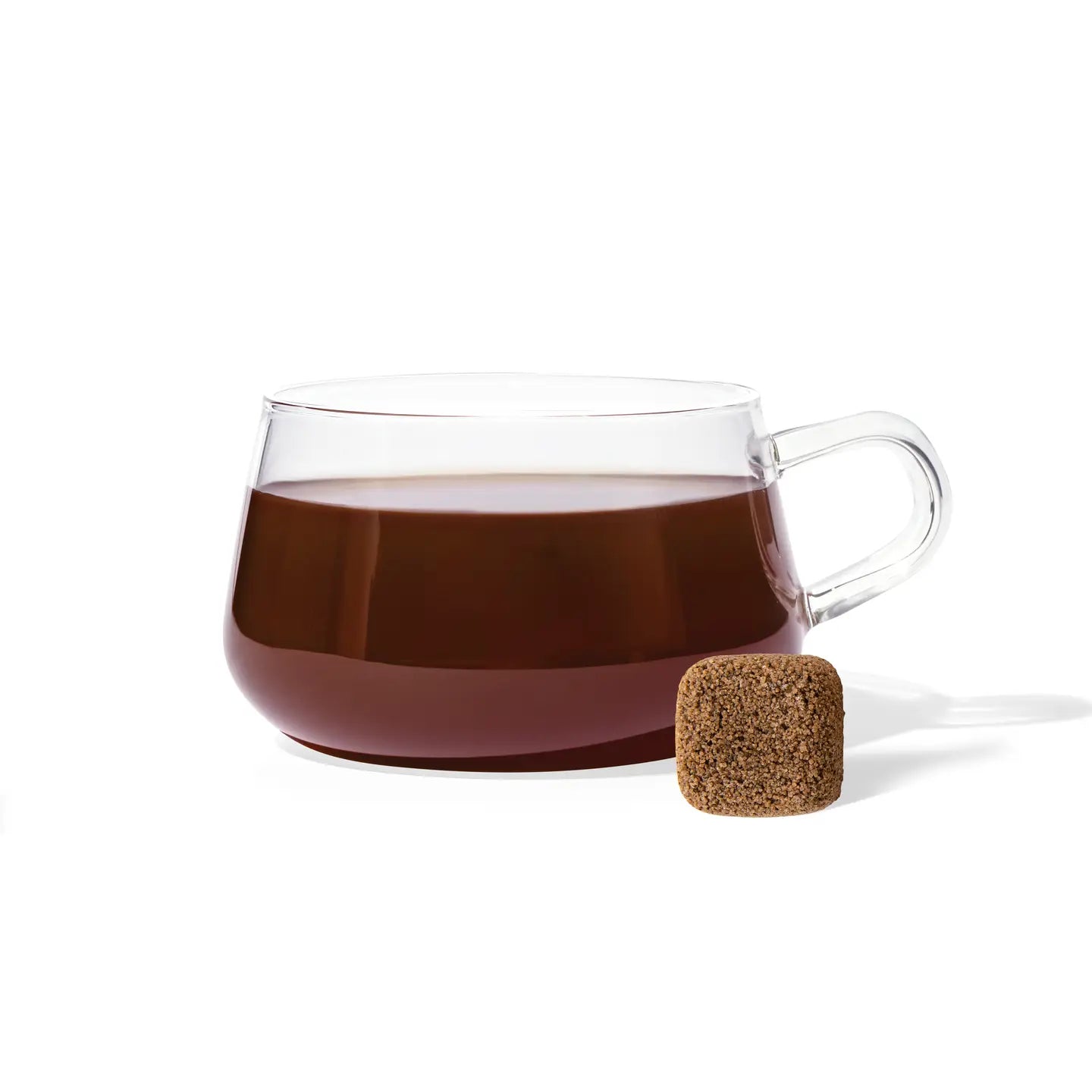 Clear glass mug with dark liquid and cork stopper on a white background